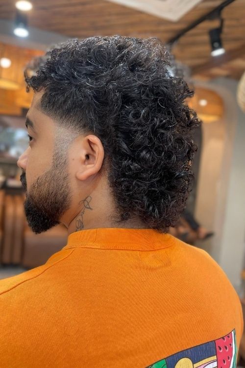 Black curly mullet with faded sides and defined texture